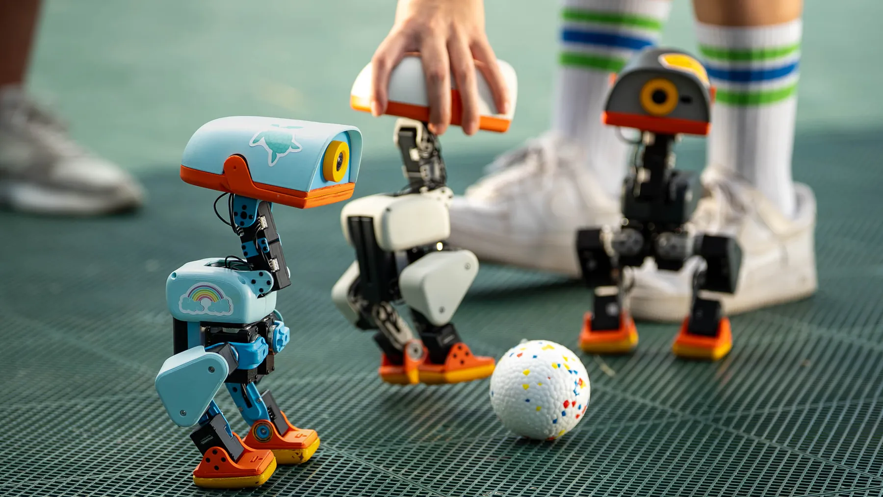 Zwei Microducks spielen auf Kunstrasen mit einem Ball